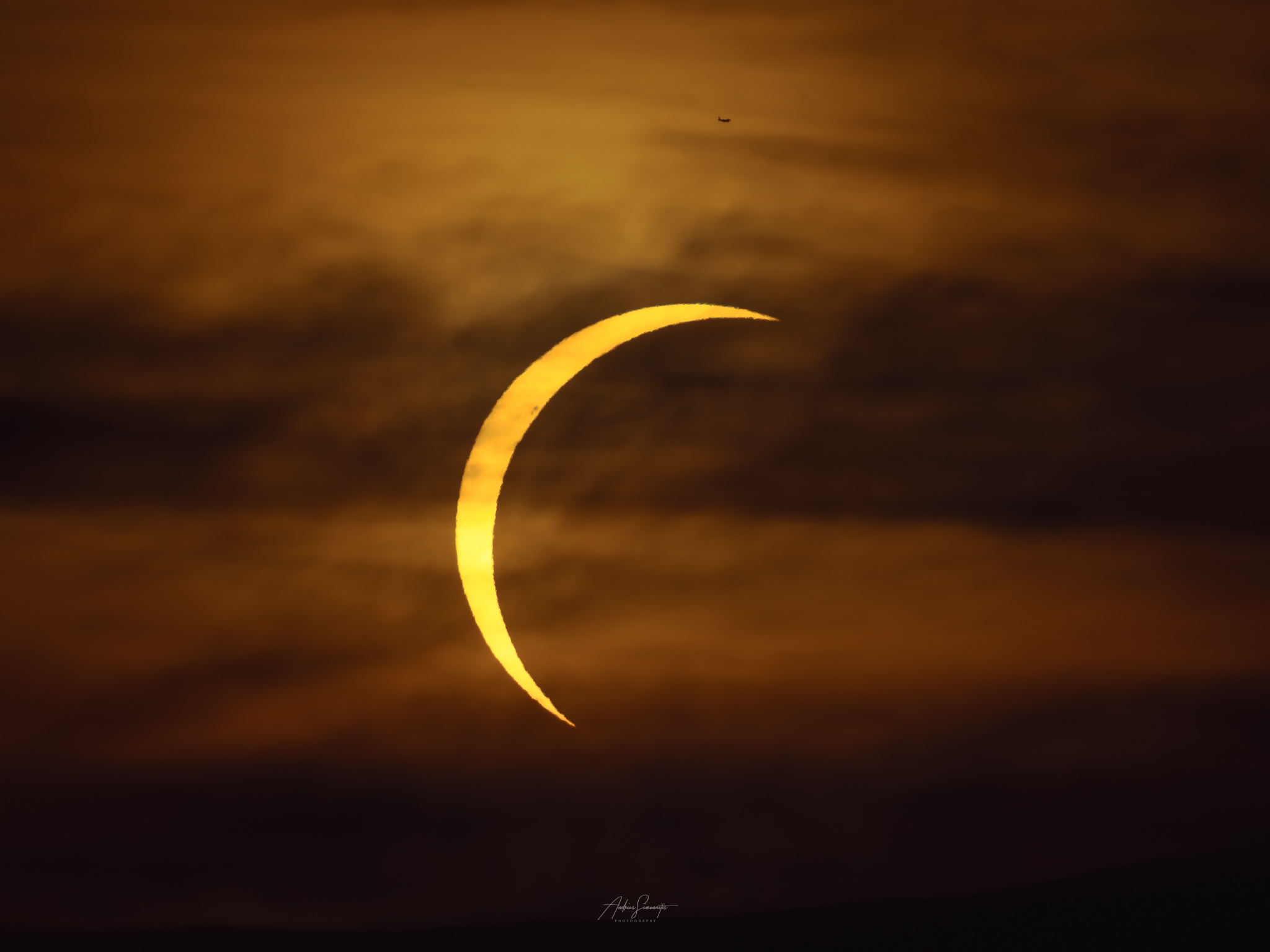 Golden solar crescent suspended in a warm cloudscape